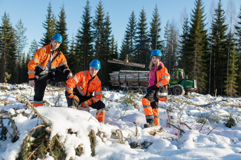 Opiskelijoita ja metsätraktori talvisessa metsässä