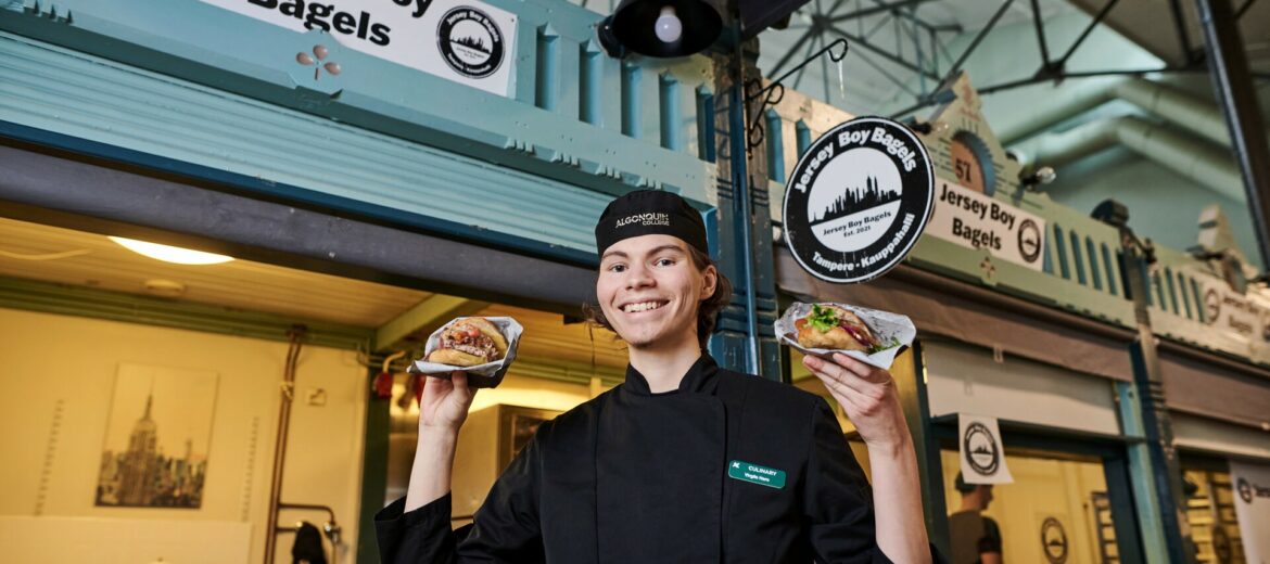 Virgile Hero hymyilee kameralle bagelit käsissään Tampereen Kauppahallissa