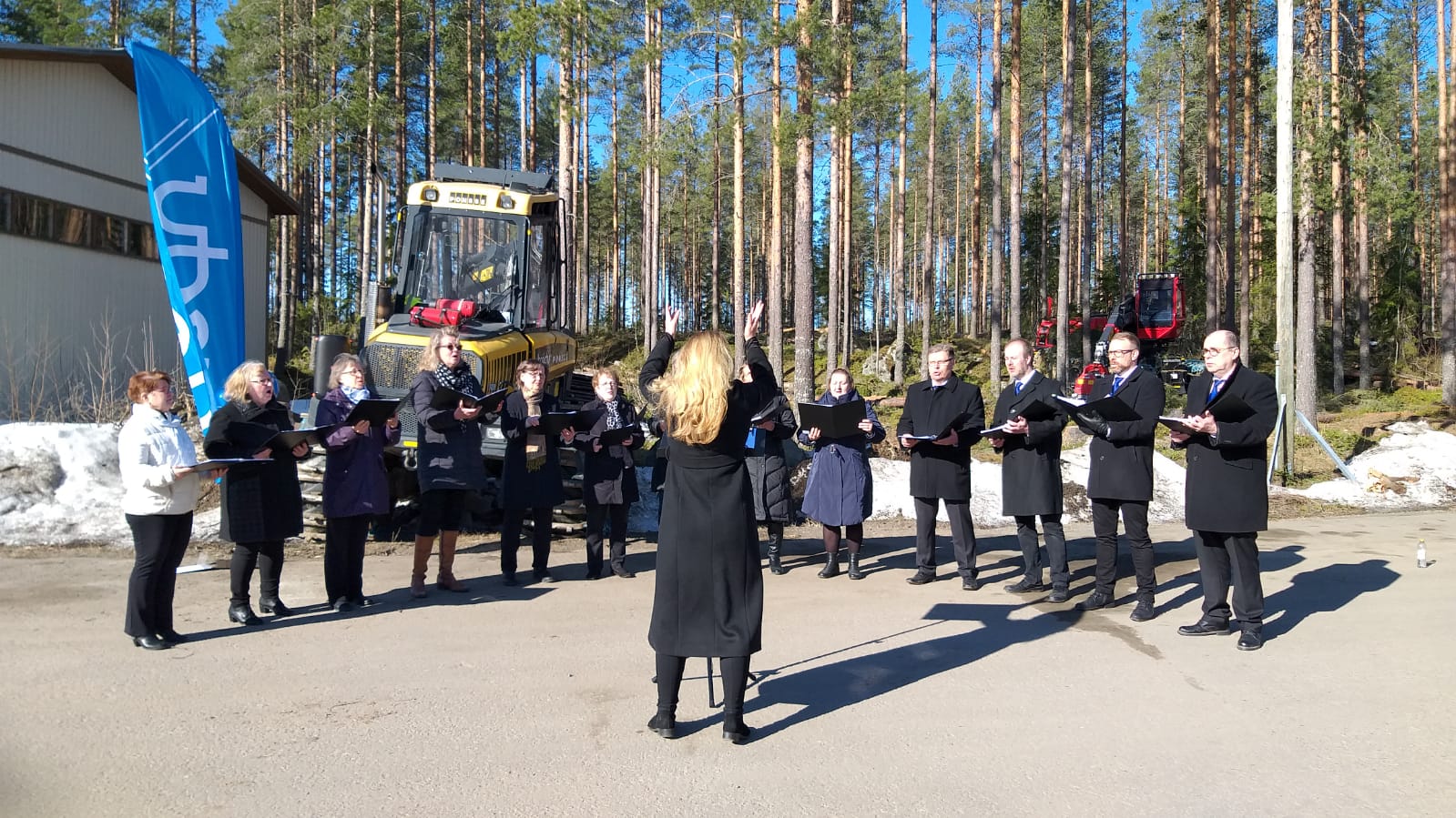 Kaiku-kuoro esiintymässä rivissä. Kuoronjohtaja edessä.