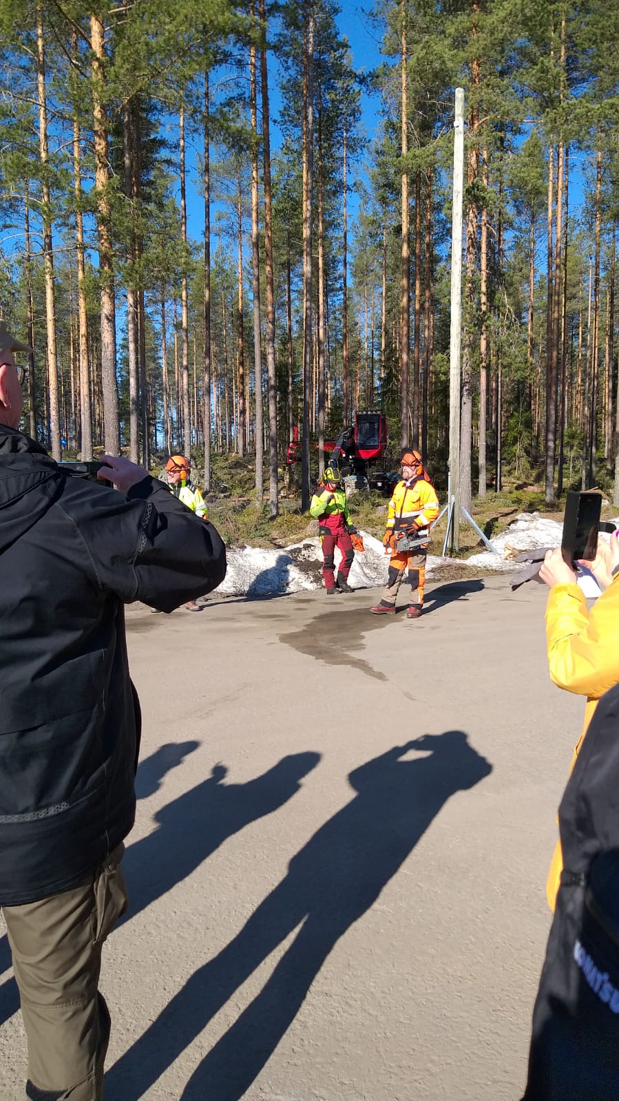 Miehiä seisomassa moottorisahat kädessä ulkona.