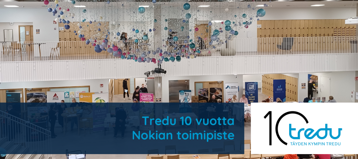 Nokian toimipiste sisältä. Aulassa on ihmisiä ja ständejä, katosta roikkuu pallotaideteos.