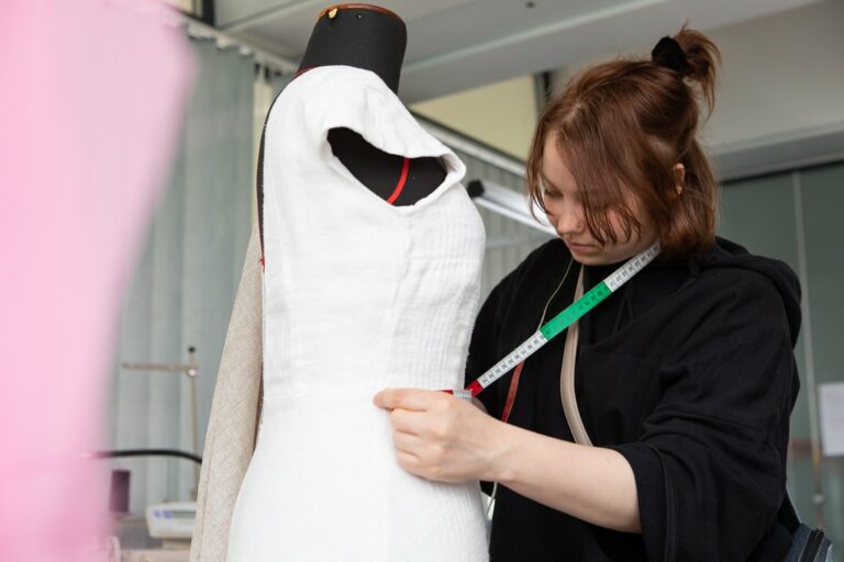 Opiskelija sovittaa vaatetta mallinuken päälle.