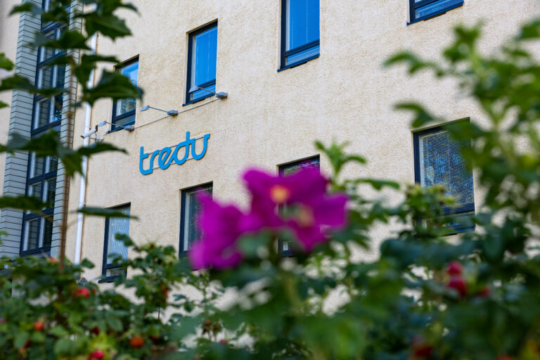Tredun oppilaitosrakennus ulkoapäin, seinässä Tredun logo.