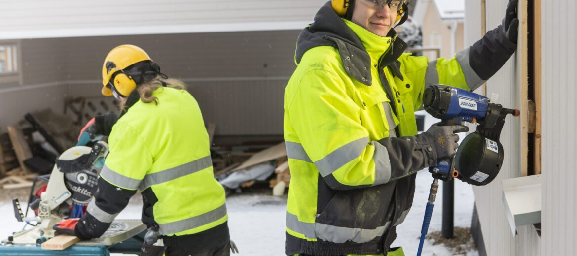 Tredun opiskelijoita rakennustyömaalla työvaatteissa.