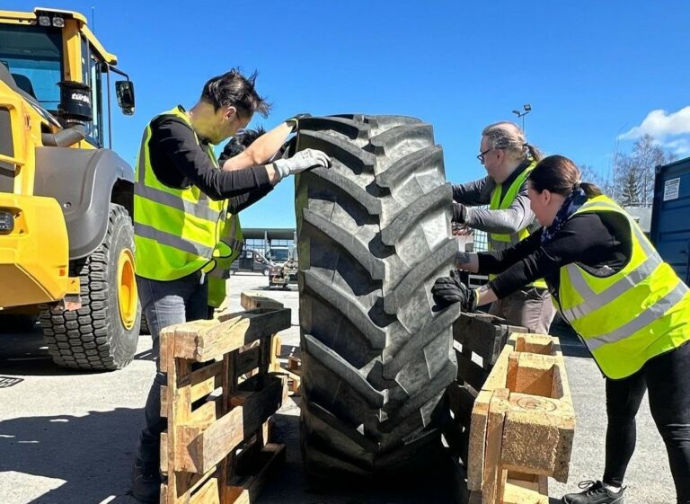 Tredun opiskelijat siirtävät traktorinrengasta.