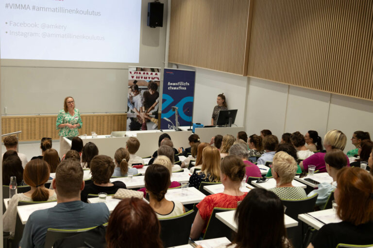 Susanna Kangas juontamassa tilaisuutta täydessä auditoriossa