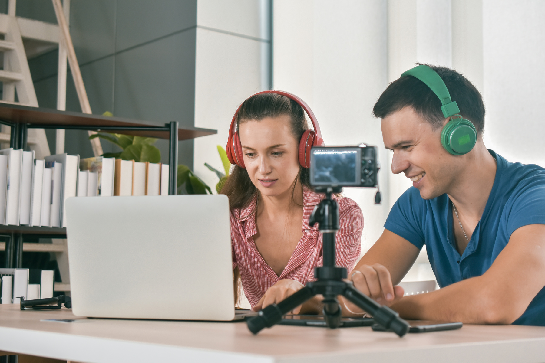 Kaksi henkilöä tekevät puhelimella markkinointivideota, kuvaavat puhe osuutta kuulokkeet päässä.