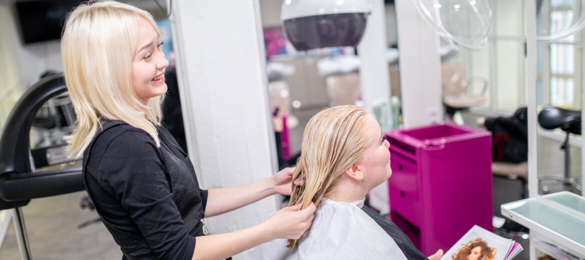 Hius- ja kauneudenhoitoalan opiskelija laittaa hiuksia.