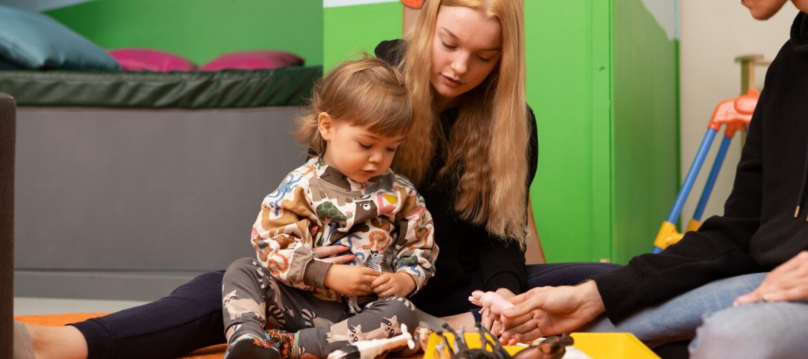 Kasvatusalan opiskelijoita leikkimässä lapsen kanssa.