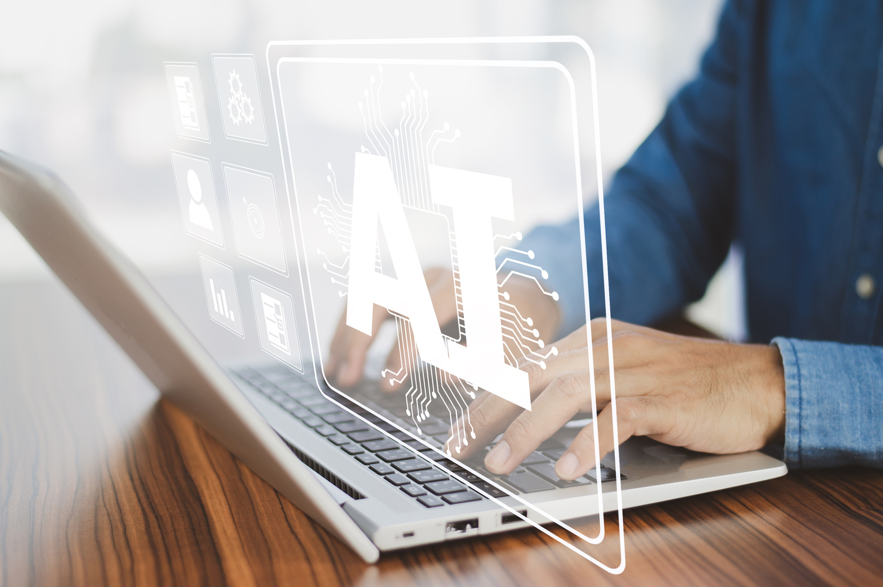 henkilö työskentelee kannettavalla tietokoneella. Kuvassa näkyy kannettava tietokone ja kädet sekä teksti AI.